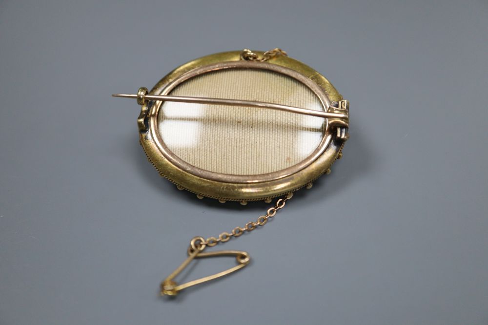 A Victorian yellow metal and diamond set oval brooch, with glazed back and safety chain, 39mm, gross 11.1 grams.
